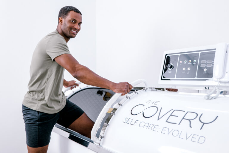Smiling man entering the Covery oxygen chamber.