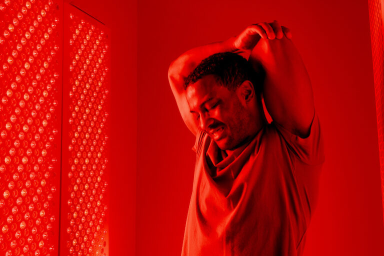 Man comfortably stretching inside a red light therapy chamber